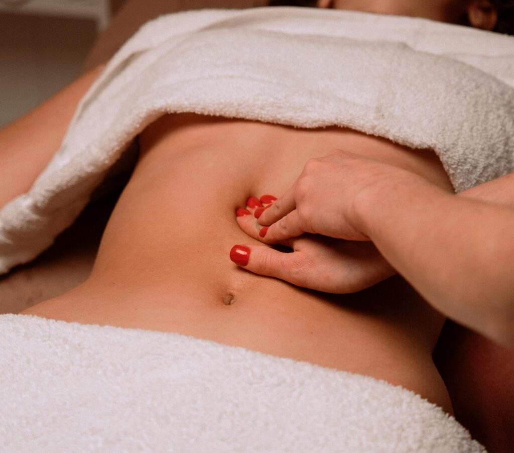 A soothing massage on a woman's abdomen with painted nails, creating a serene spa atmosphere.